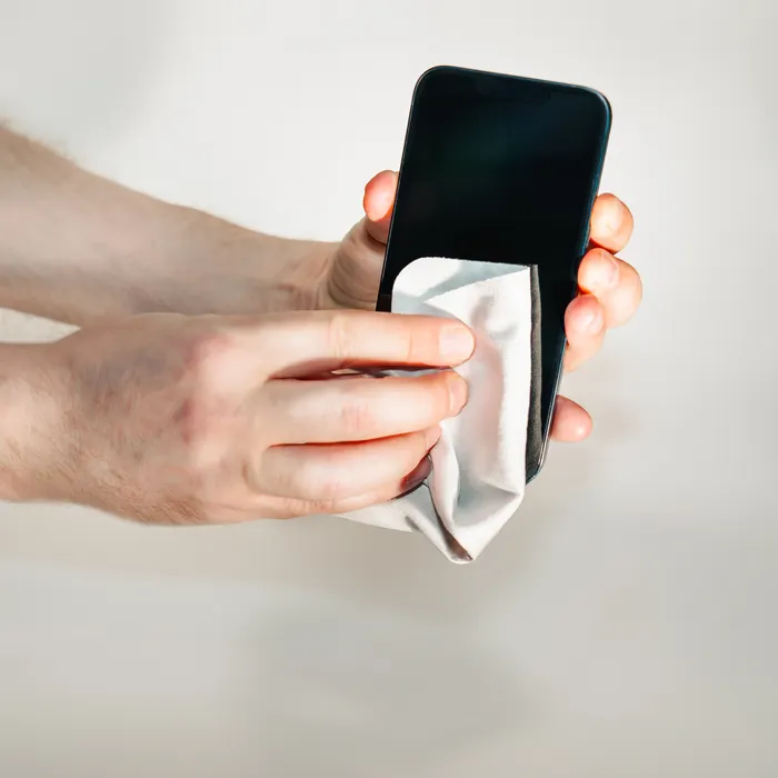 A phone being wiped with a microfiber cloth