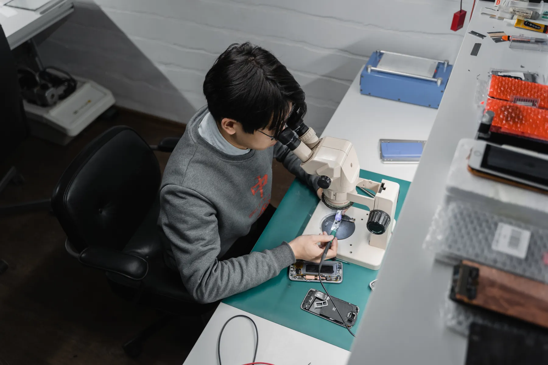 Technician carefully repairing a phone under a microscope