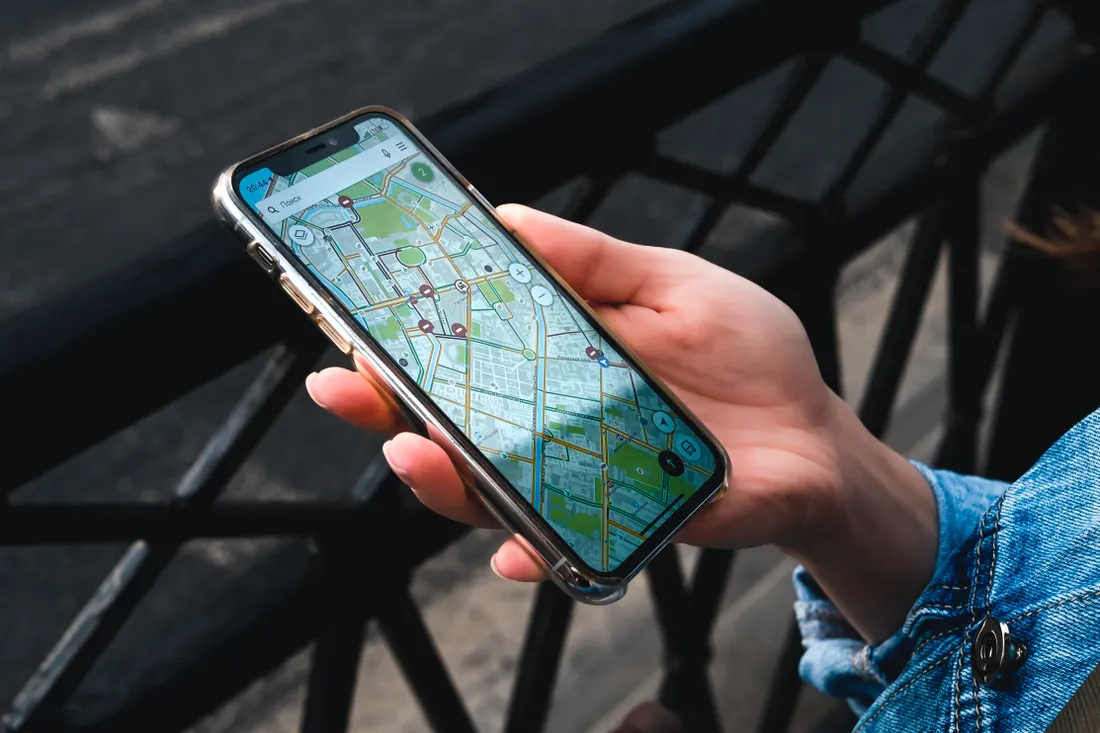 Stock photograph of a hand holding a phone with a navigation map