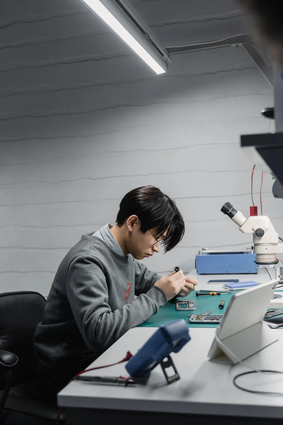 Stock photograph of a technician examining electronics at a workbench